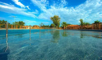a pool of water with trees and a fence at Les mobil homes de NOLY TV CLIM 6places in Port-la-Nouvelle