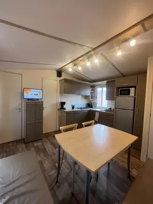 a kitchen with a wooden table and a table and chairs at Les mobil homes de NOLY TV CLIM 6places in Port-la-Nouvelle