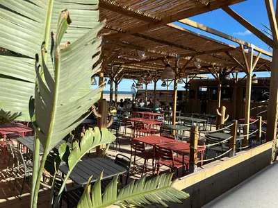 a restaurant with red tables and chairs and the ocean at Les mobil homes de NOLY TV CLIM 6places in Port-la-Nouvelle