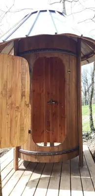 a wooden dog house with an umbrella on a deck at Le tipi à Marie, déconnectez- vous !!! in Cambounès