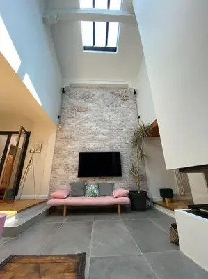 a living room with a couch in front of a brick wall at Maison de famille (piscine, jacuzzi et sauna) in Quillan