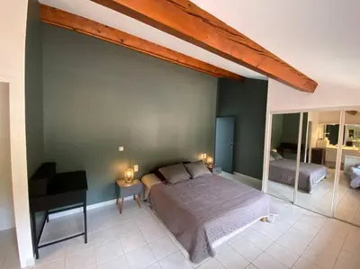 a bedroom with a large bed and a desk at Maison de famille (piscine, jacuzzi et sauna) in Quillan