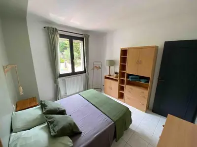 a bedroom with a large bed and a window at Maison de famille (piscine, jacuzzi et sauna) in Quillan
