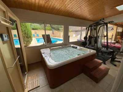 a large bath tub in a room with a gym at Maison de famille (piscine, jacuzzi et sauna) in Quillan