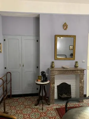 a living room with a fireplace and a mirror at La Maison du Magistrat in Durban-Corbières