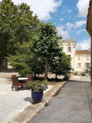 a patio with a table and a tree and a building at Le soleil d Eugènie appartement dans résidence avec Piscine commune près de Carcassonne in Olonzac