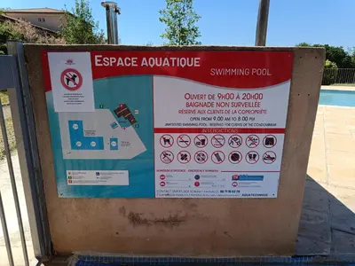 a sign is posted next to a swimming pool at Le soleil d Eugènie appartement dans résidence avec Piscine commune près de Carcassonne in Olonzac