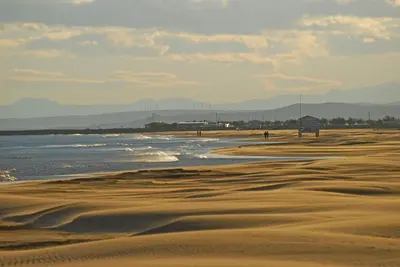 a beach with sand and water and mountains in the background at Magnifique Studio sur le Port de Gruissan (2 à 4 pers) in Gruissan