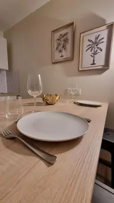 a white plate sitting on a table with wine glasses at Magnifique Studio sur le Port de Gruissan (2 à 4 pers) in Gruissan