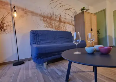 a blue couch and a table with two wine glasses at Magnifique Studio sur le Port de Gruissan (2 à 4 pers) in Gruissan