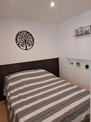 a bedroom with a bed with a tree sticker on the wall at Bel appartement 2/4personnes in Douzens