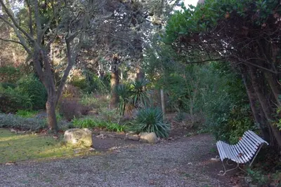 a white bench sitting in the middle of a garden at Gîte de l'arbre perché à Langel in Armissan