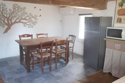 a kitchen with a table with chairs and a refrigerator at Gîte de l'arbre perché à Langel in Armissan