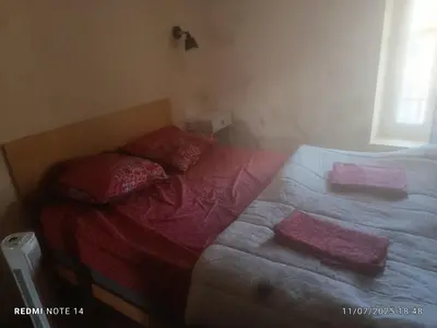 a bed with two pillows on it in a room at chambre double avec cuisine salon salle d'eau et cour avec barbecu en commun in Sigean