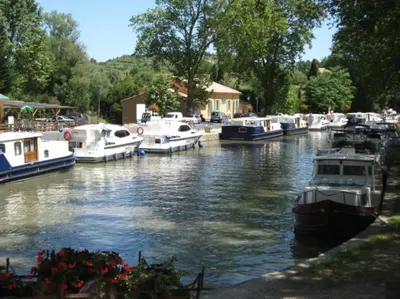 a bunch of boats are docked in a river at OCC34 - Capestang - Manoir in Capestang