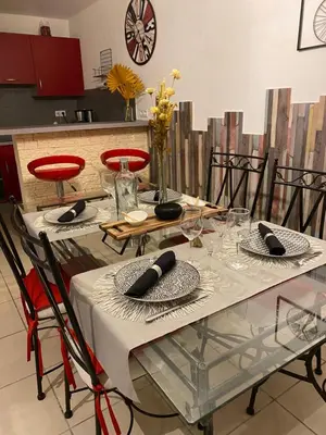 a dining table with red chairs and a white table cloth at Gîte Romarin avec SPA in Saint-Jean-de-Barrou
