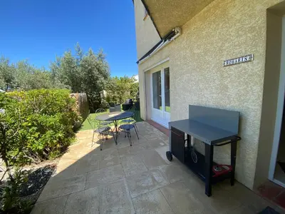 a patio with a table and chairs next to a building at Gîte Romarin avec SPA in Saint-Jean-de-Barrou
