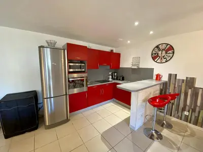 a kitchen with red cabinets and a stainless steel refrigerator at Gîte Romarin avec SPA in Saint-Jean-de-Barrou