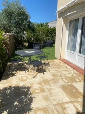 a patio with a table and chairs in a yard at Gîte Romarin avec SPA in Saint-Jean-de-Barrou