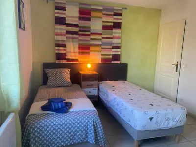 a bedroom with two beds and a colorful wall at Gîte Romarin avec SPA in Saint-Jean-de-Barrou