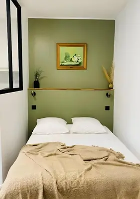 a bed in a bedroom with a green wall at Studio mosaïque Narbonne in Narbonne