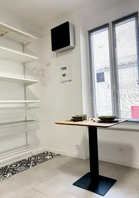 a table in a room with a tv and shelves at Studio mosaïque Narbonne in Narbonne