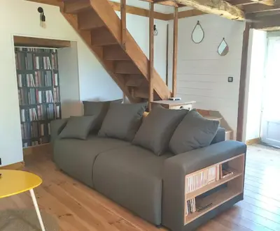 a couch in a living room with a staircase at Gîte du Fassac in Saint-Julien-du-Puy