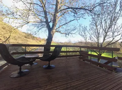 a wooden deck with a picnic table and a tree at Gîte du Fassac in Saint-Julien-du-Puy