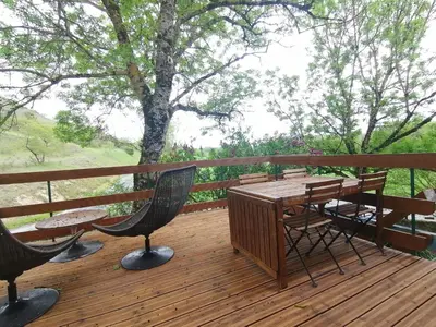 a wooden deck with a table and chairs on it at Gîte du Fassac in Saint-Julien-du-Puy