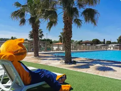 a stuffedanimal sitting in a lawn chair next to a swimming pool at Les mobil homes de Naka, 6 places, TV, CLIM in Port-la-Nouvelle