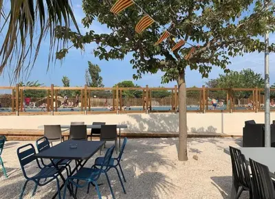a table and chairs with a tree and a fence at Les mobil homes de Naka, 6 places, TV, CLIM in Port-la-Nouvelle