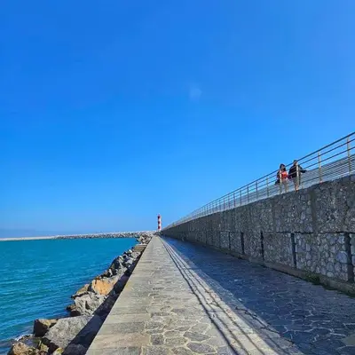 a pier next to the water with a lighthouse at Les mobil homes de Naka, 6 places, TV, CLIM in Port-la-Nouvelle