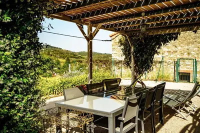 a table and chairs under a wooden pergola at Côté Grange à Bélesta in Bélesta