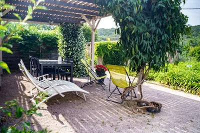 a patio with a table and chairs under a pergola at Côté Grange à Bélesta in Bélesta
