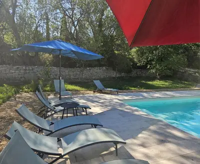 a group of chairs and umbrellas next to a pool at Maison vigneronne de Bonne Maman - climatisée in Cesseras