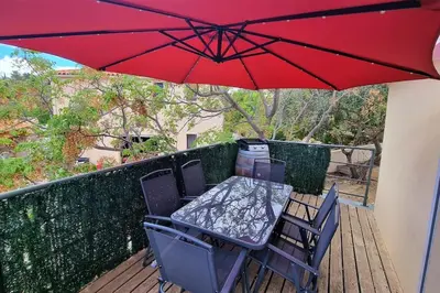 a table and chairs under a red umbrella on a deck at Villa d'Architecte - Cocon Design, Calme & Mer in Fitou