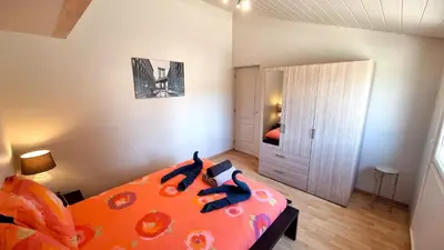 a bedroom with a bed with an orange comforter at Villa d'Architecte - Cocon Design, Calme & Mer in Fitou