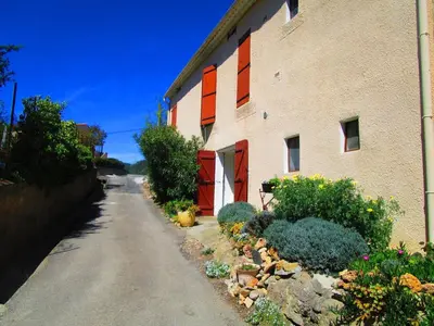 a building with orange windows and plants next to a street at Maison champêtre à Tournissan avec grand jardin in Tournissan