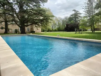 a swimming pool with blue water in a yard at Gîte de l'Abbé 8 à 10 personnes in Lempaut