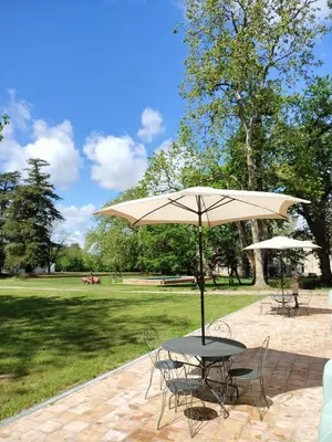 a table and chairs with an umbrella in a park at Gîte de l'Abbé 8 à 10 personnes in Lempaut