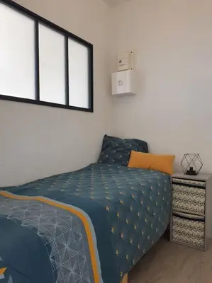 a bedroom with a bed with a blue comforter and two windows at Au bord de l'eau, Profitez d'un moment de calme ! in Gruissan