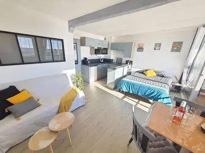 a large room with a bed and a kitchen at Au bord de l'eau, Profitez d'un moment de calme ! in Gruissan