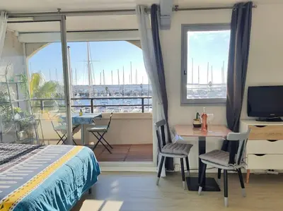 a bedroom with a bed and a desk and a balcony at Au bord de l'eau, Profitez d'un moment de calme ! in Gruissan