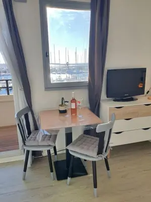 a table and chairs in a room with a window at Au bord de l'eau, Profitez d'un moment de calme ! in Gruissan