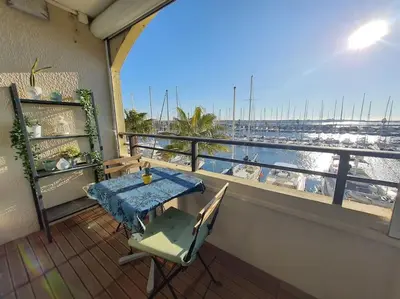 a balcony with a table and a view of a harbor at Au bord de l'eau, Profitez d'un moment de calme ! in Gruissan