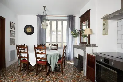 a dining room with a table and chairs and a clock at The French House in Quillan in Quillan