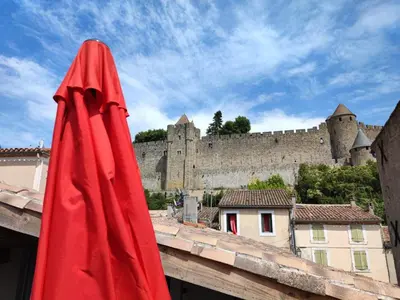 a red umbrella on top of a building with a castle at La Terrasse du Temps Jadis in Carcassonne