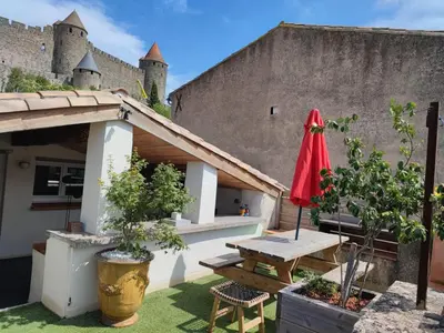 a patio with a table and a red umbrella at La Terrasse du Temps Jadis in Carcassonne
