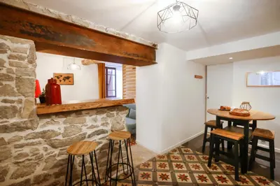 a room with a stone wall and a table and stools at Studio du Charme Médiéval ConciergerieDameCarcas in Carcassonne