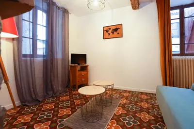 a living room with two tables and a tv at Studio du Charme Médiéval ConciergerieDameCarcas in Carcassonne